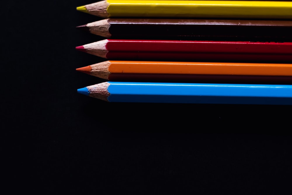 a row of colored pencils on a black surface