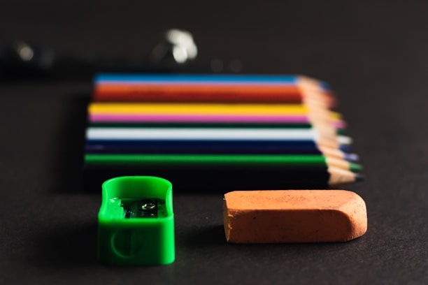 a group of colored pencils next to a sharpener