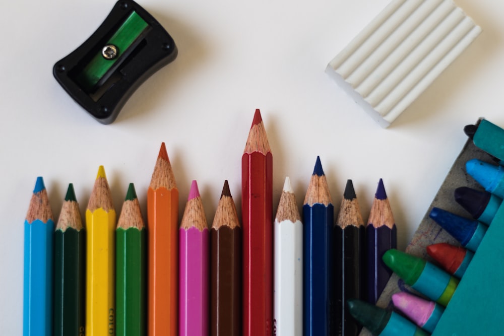 a group of colored pencils sitting next to a sharpener