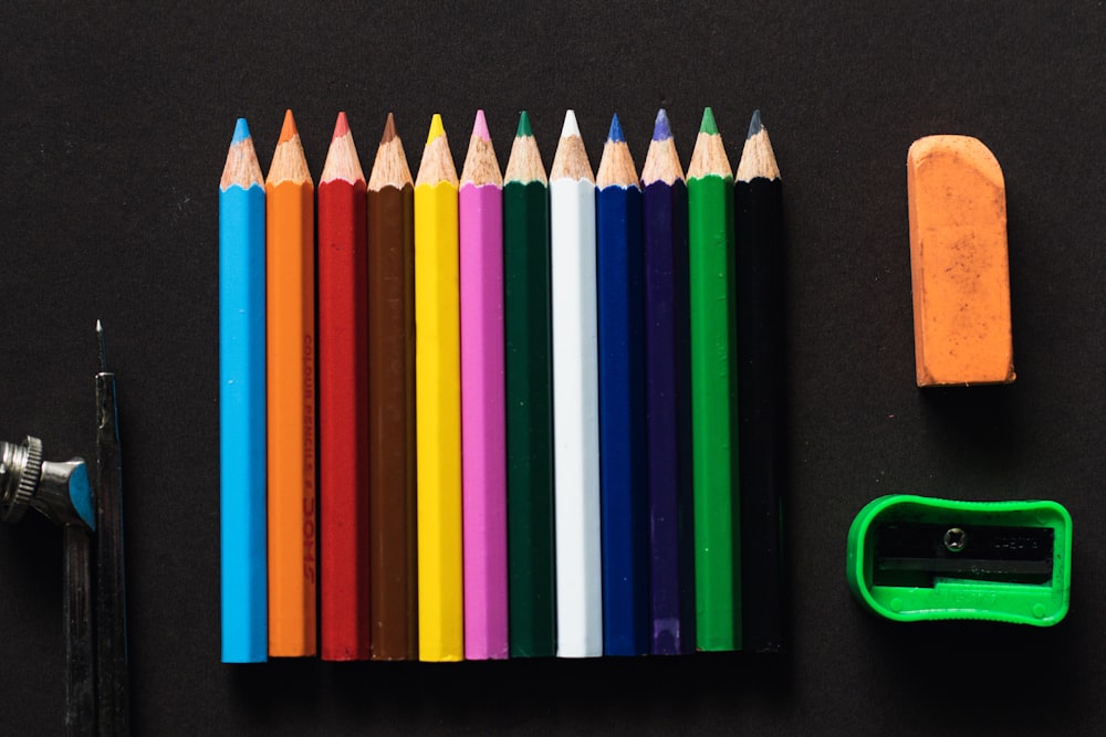 a group of colored pencils sitting next to a sharpener