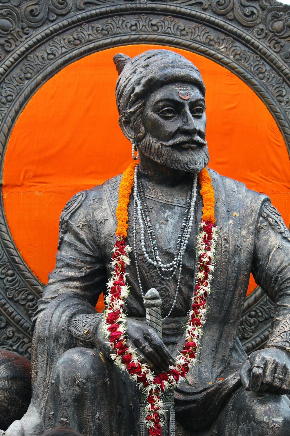 Eine Statue eines Mannes, der vor einem orangefarbenen Kreis sitzt
