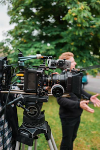 a woman standing next to a camera on top of a tripod