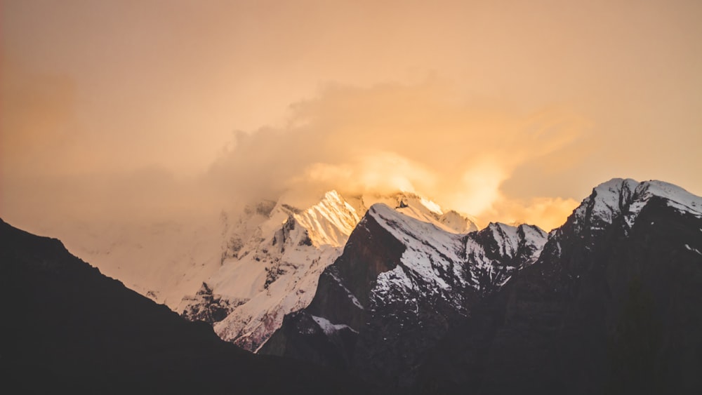 a mountain covered in snow under a cloudy sky