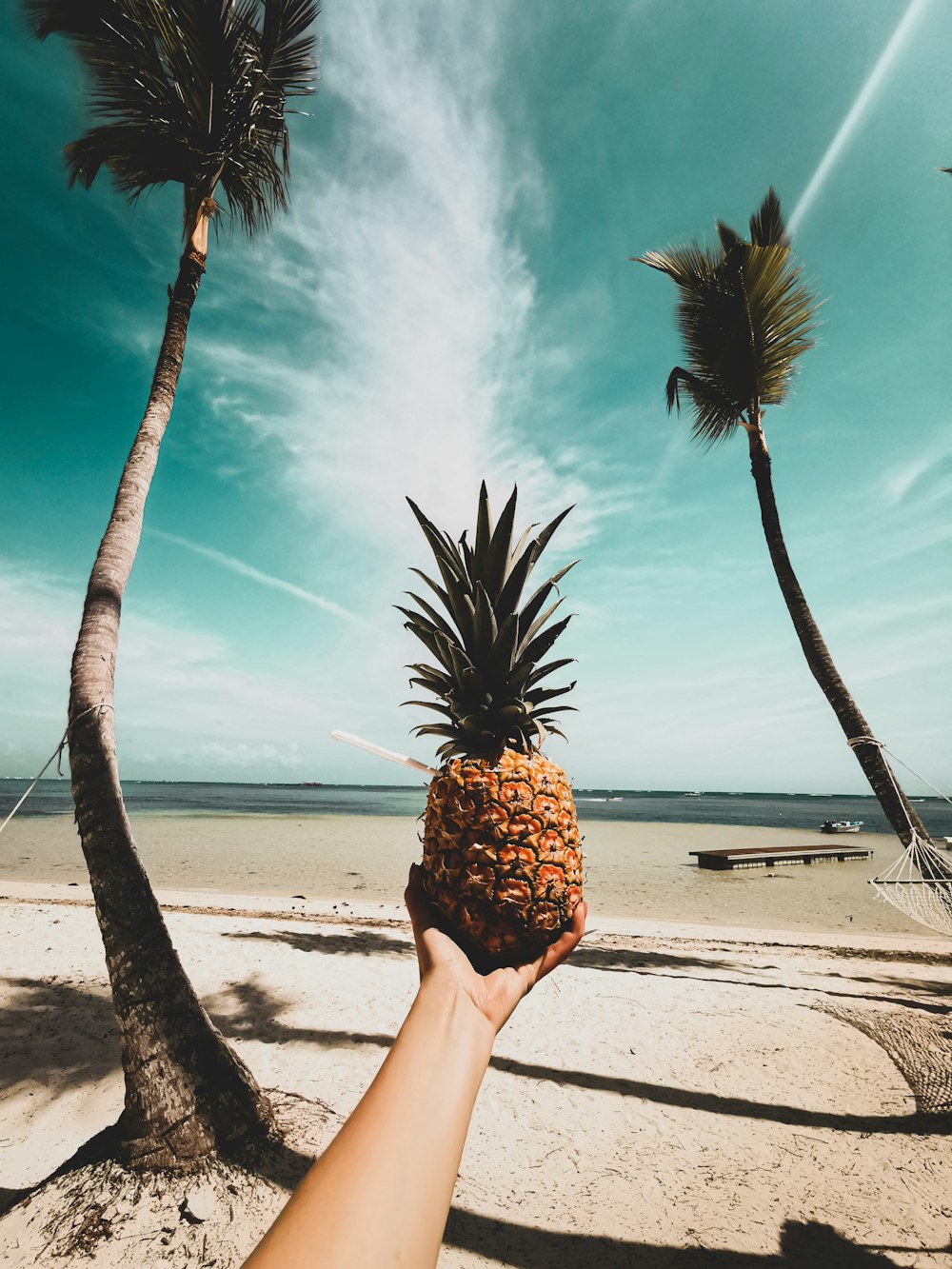 a person holding up a pineapple on a beach