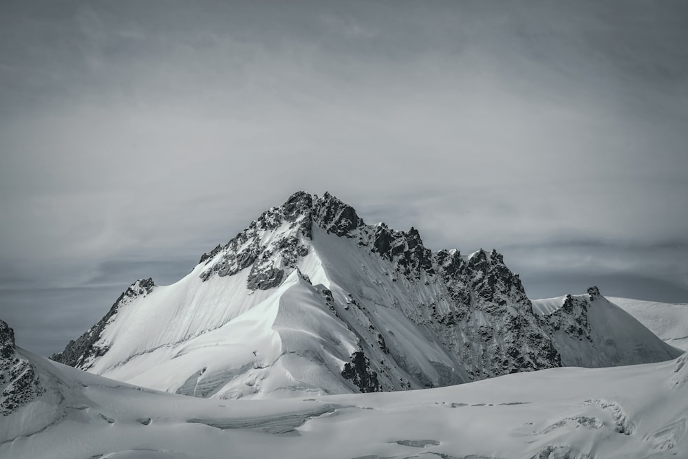 a mountain covered in snow under a cloudy sky