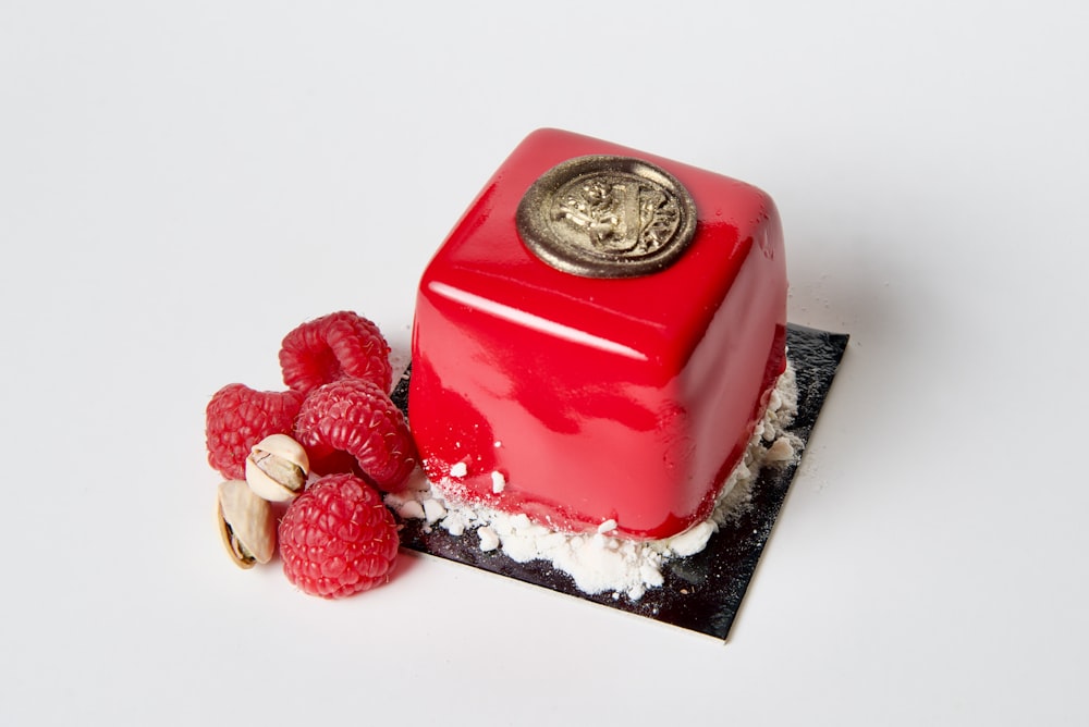 a red cake with raspberries and nuts on a plate