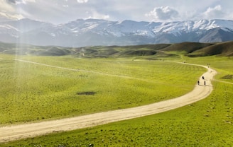 a couple of people walking down a dirt road