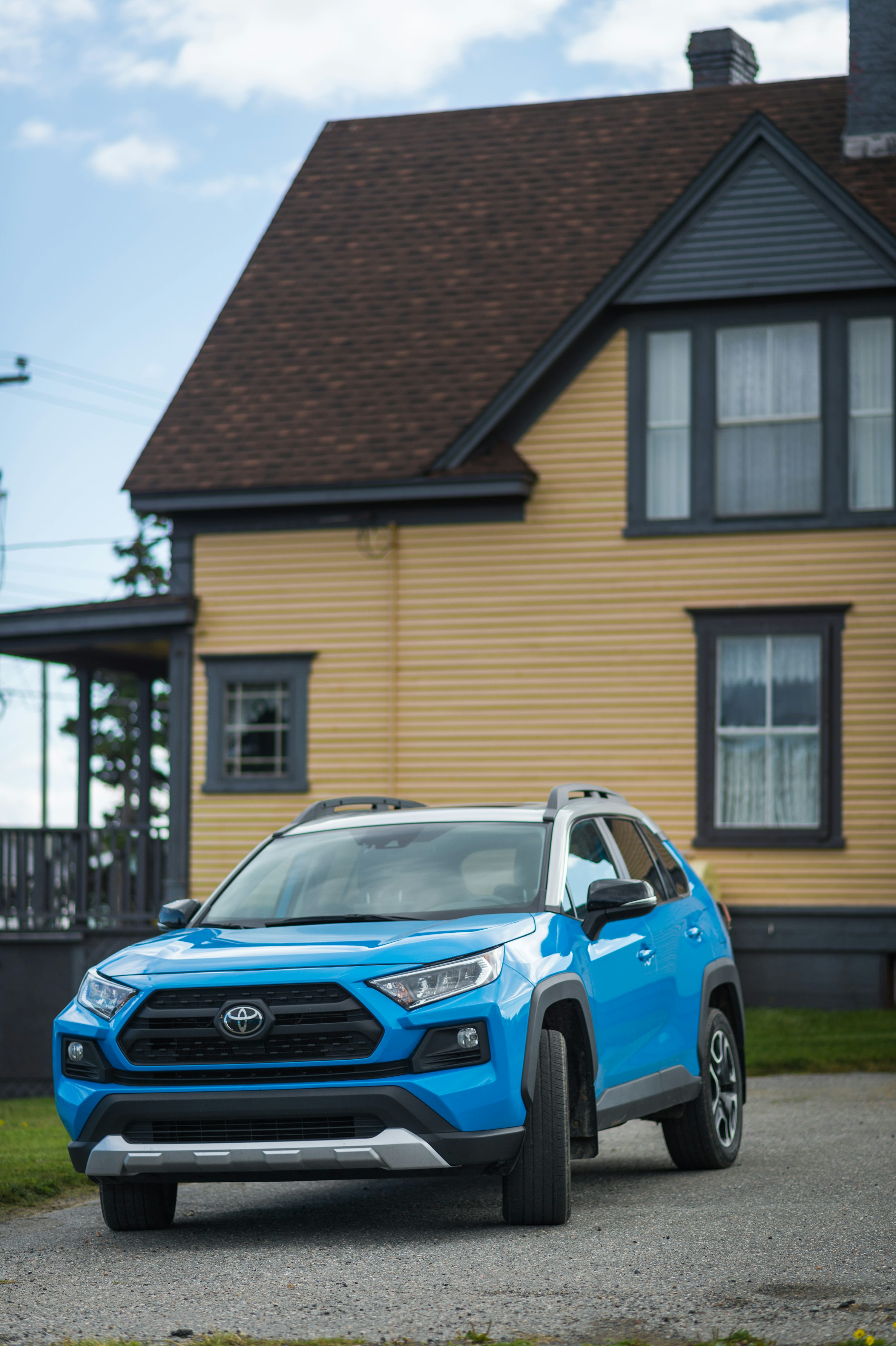a blue toyota rav parked in front of a house