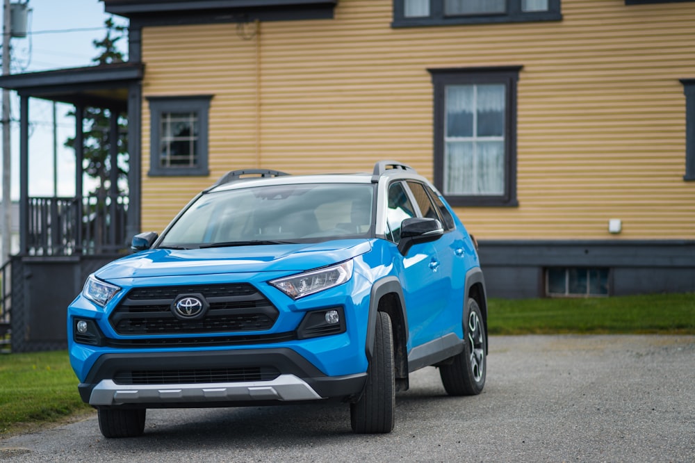 um Toyota Rav azul estacionado em frente a uma casa