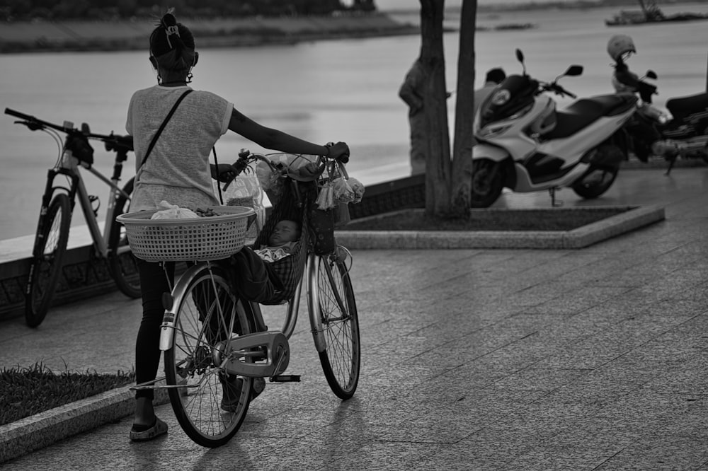 a woman riding a bike next to a body of water