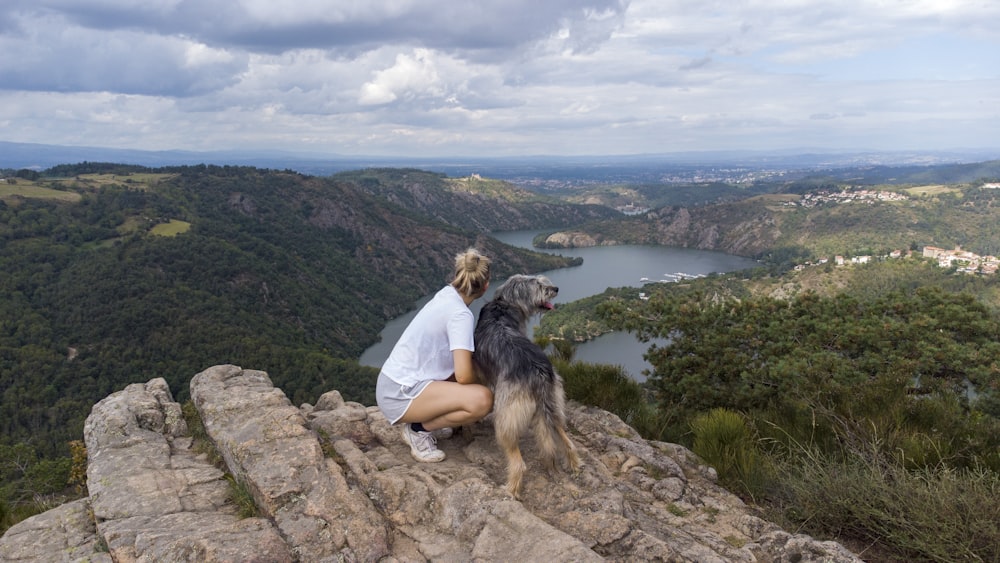 a woman sitting on a rock with a dog