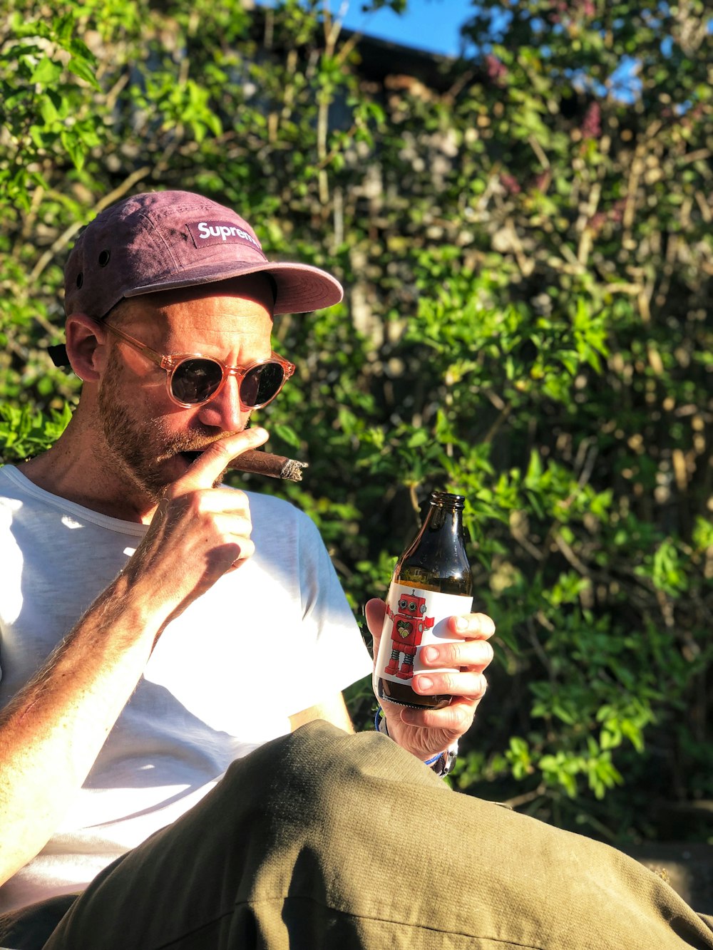 a man sitting on a bench with a beer in his hand