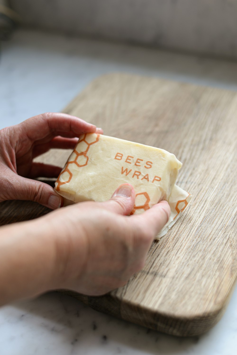 una persona sosteniendo un trozo de queso en una tabla de cortar