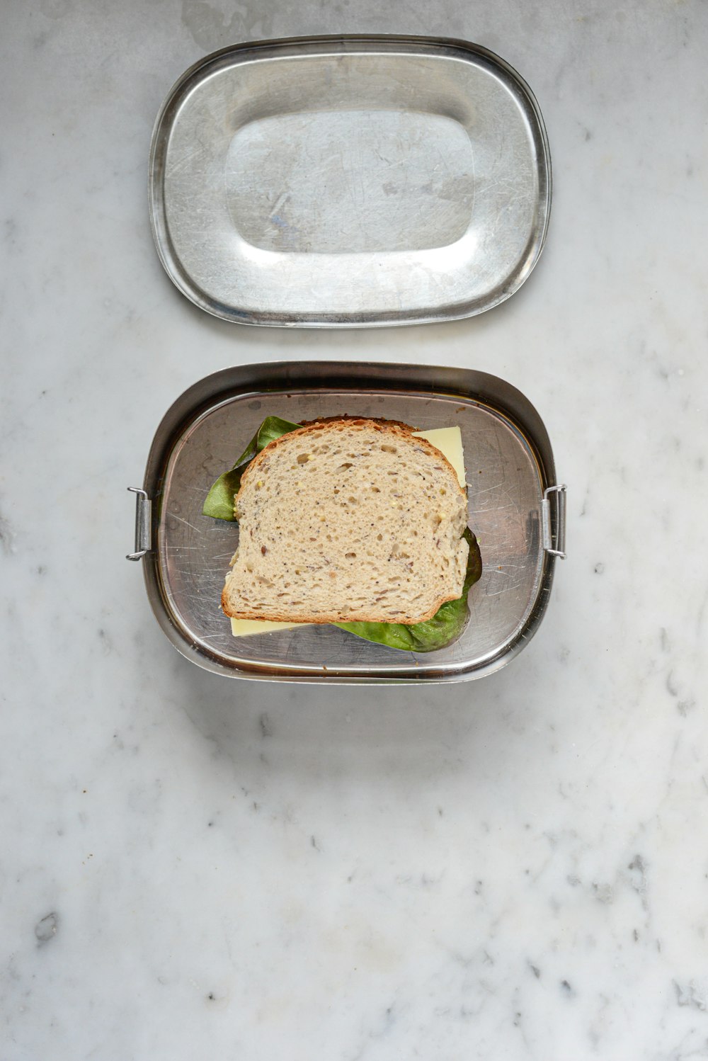 a sandwich in a metal container on a marble table
