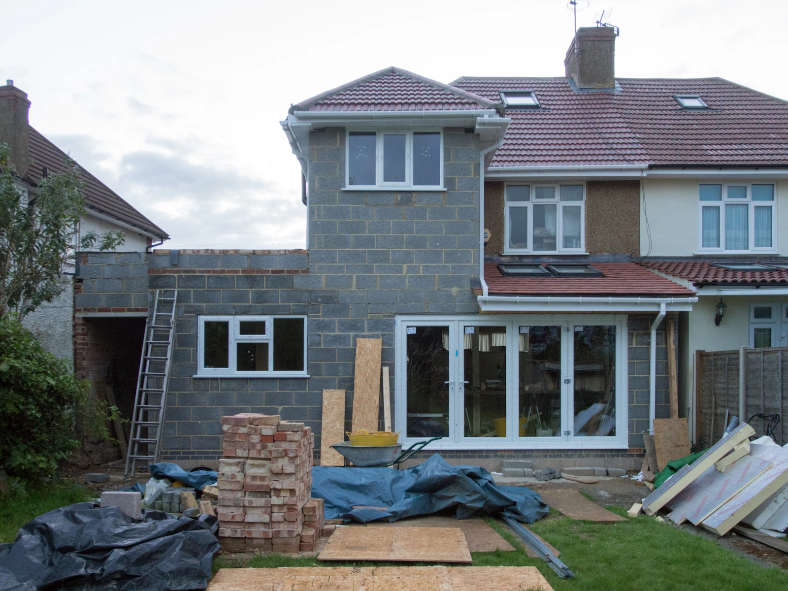 Blockwork rear extension under construction with materials in the garden