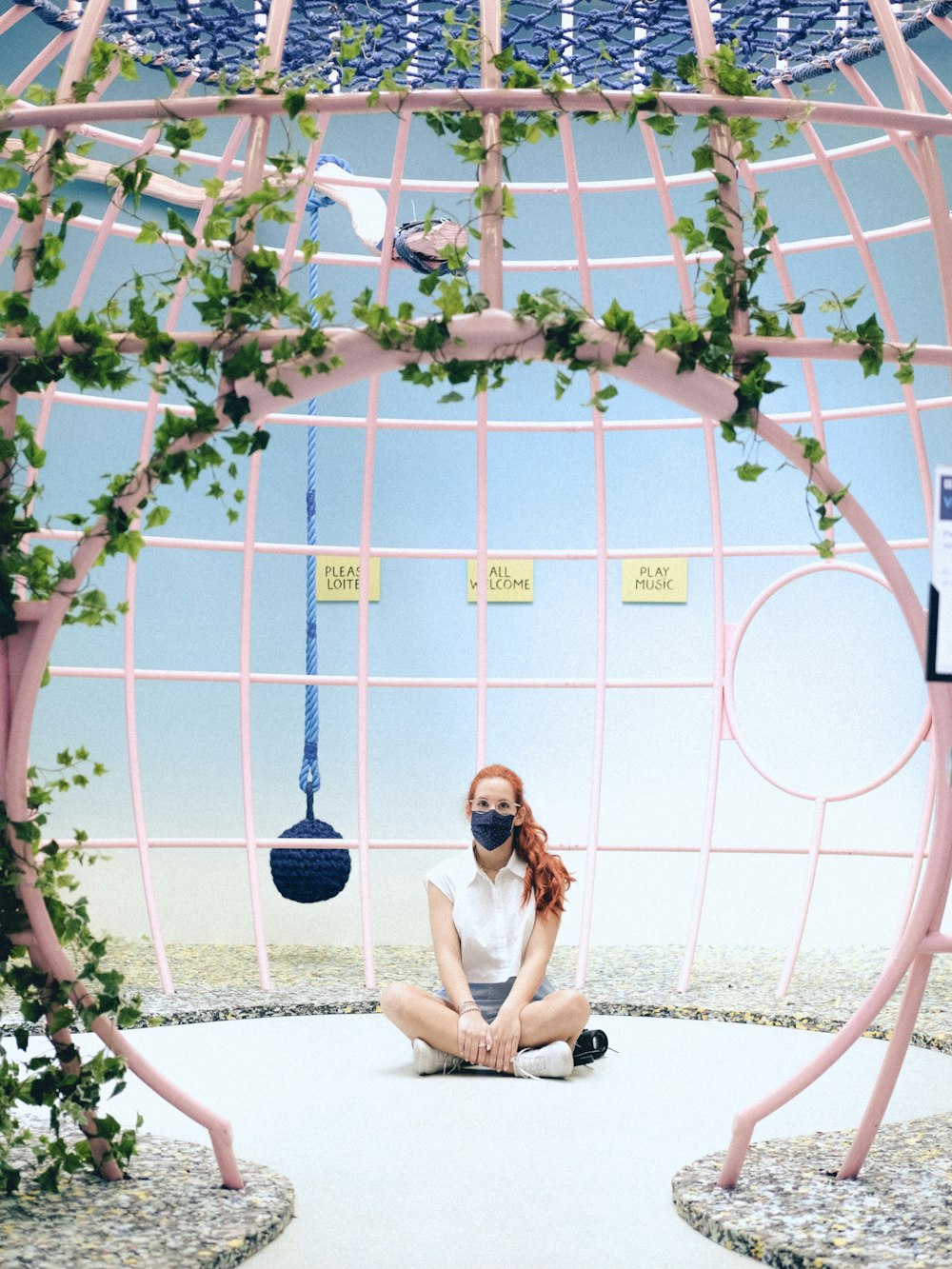 a woman sitting on the ground in front of a sculpture