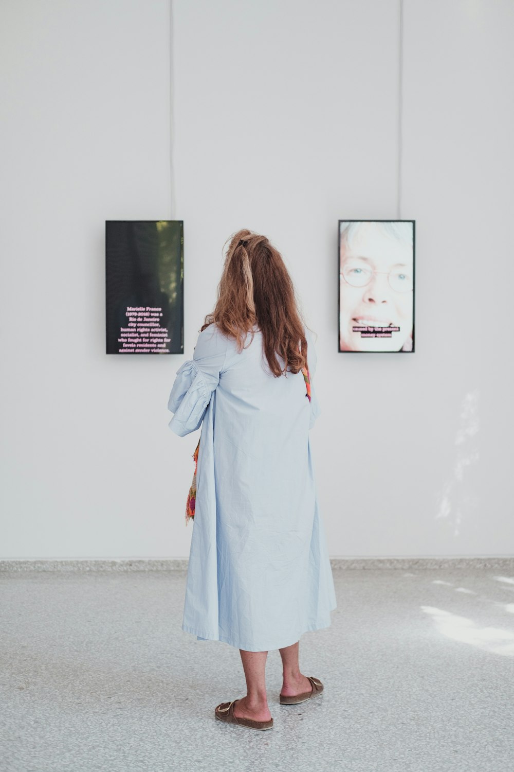 a woman standing in front of a wall with pictures on it