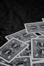 A pile of playing cards featuring intricate, symmetrical patterns on their backs, placed on a dark surface.