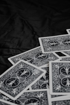 A pile of playing cards featuring intricate, symmetrical patterns on their backs, placed on a dark surface.