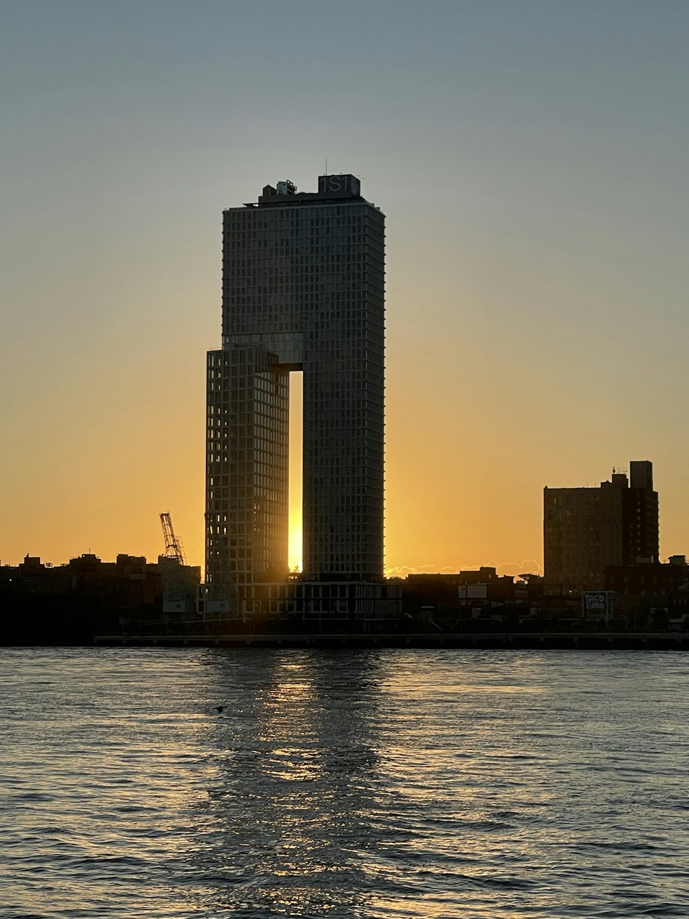the sun is setting behind a tall building