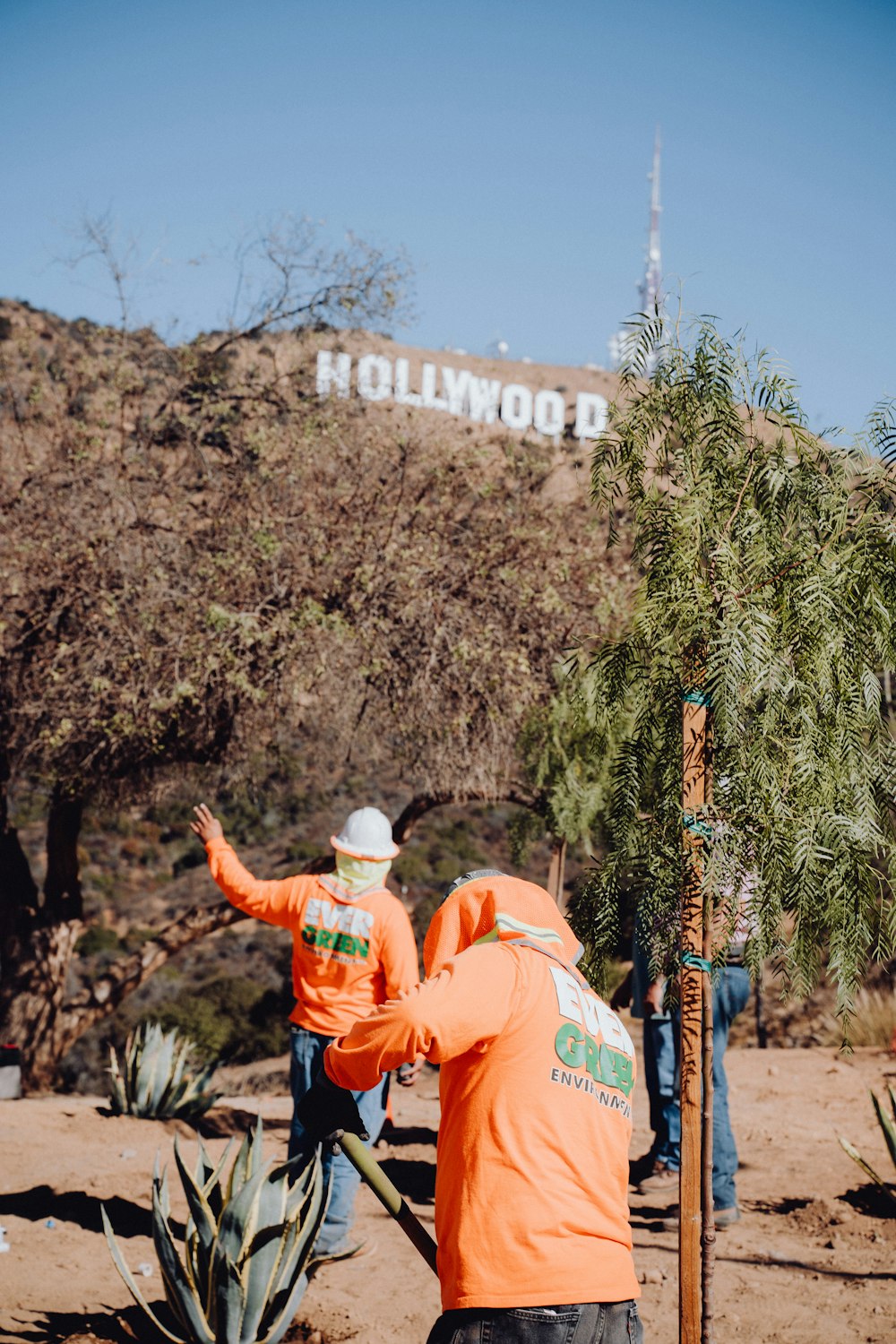 a man in an orange shirt is pointing at a sign