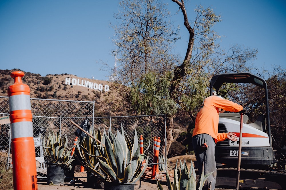 a man in an orange shirt is working on a fence