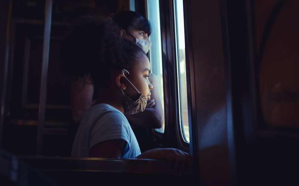 a young girl looking out the window of a train