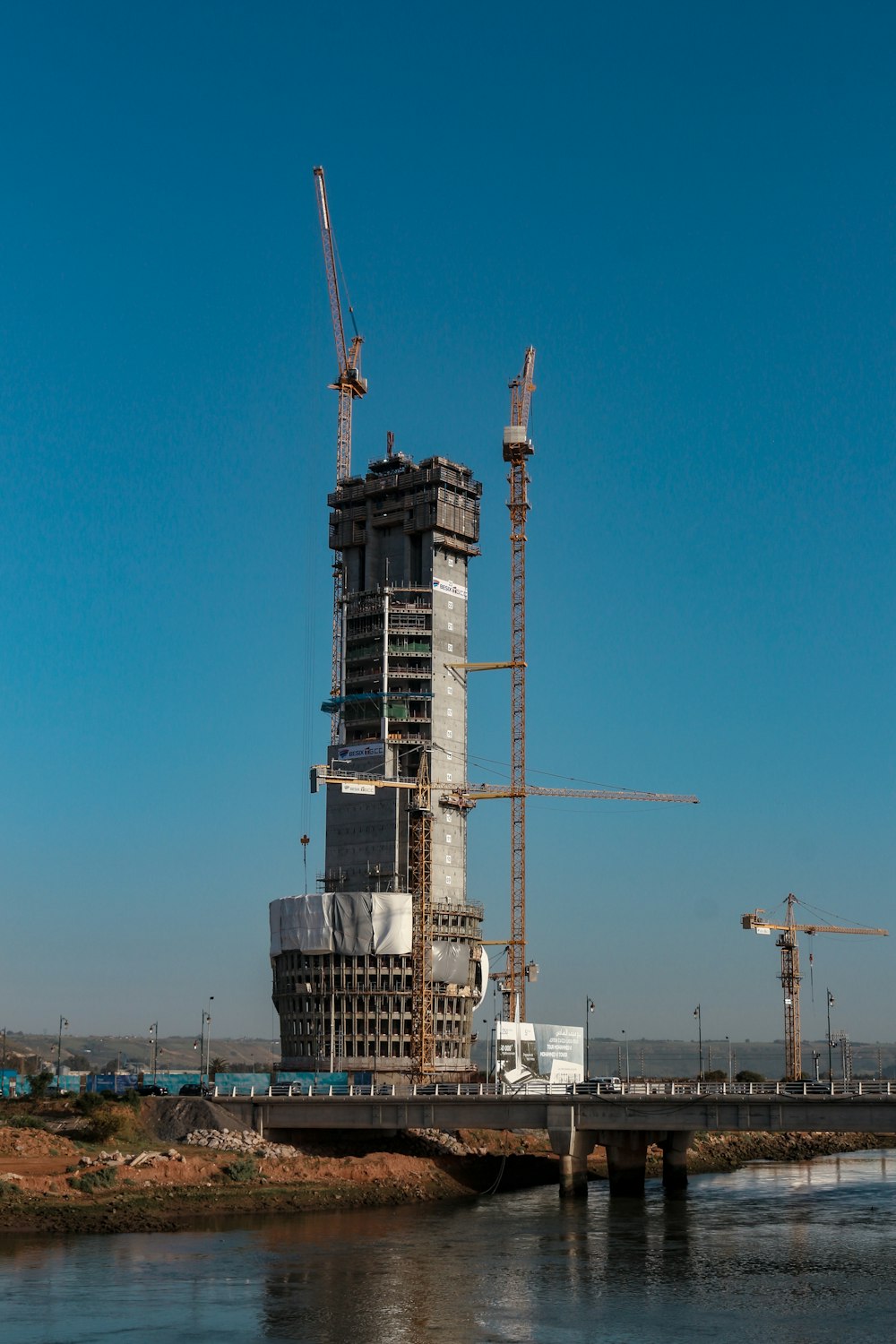 a tall building under construction next to a body of water