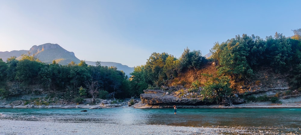 a man is wading in a river surrounded by mountains