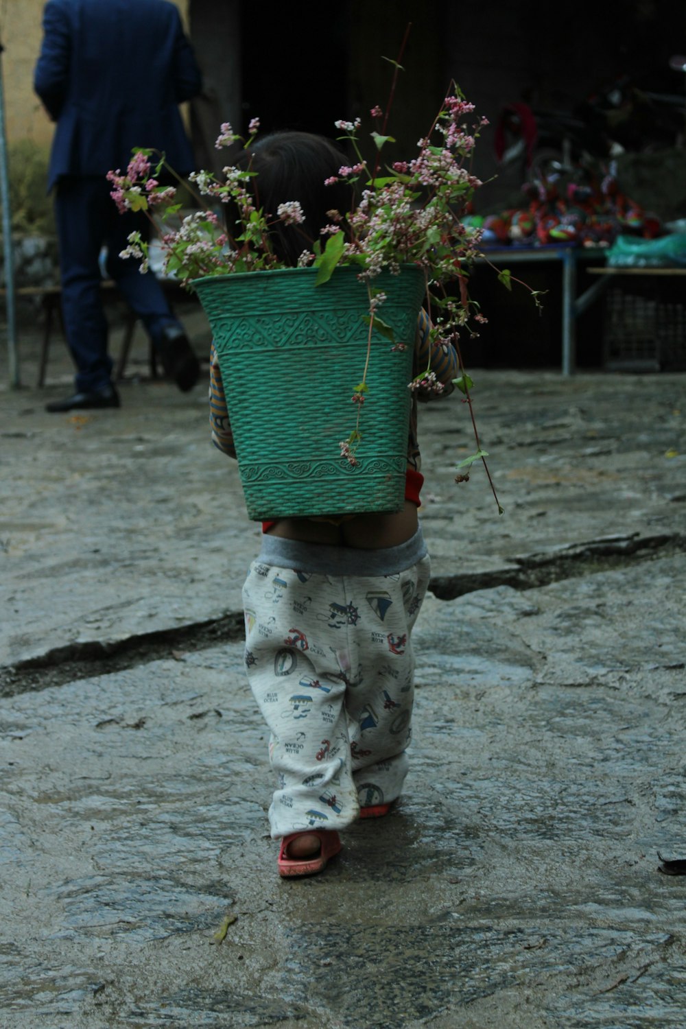 a child carrying a basket of flowers on his head