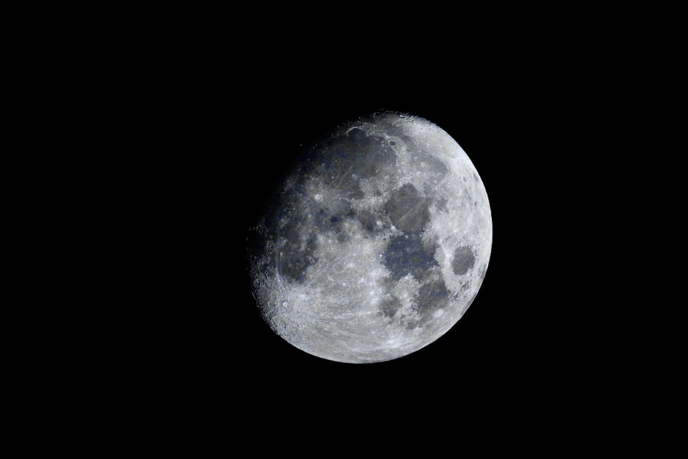 a full moon is seen in the dark sky