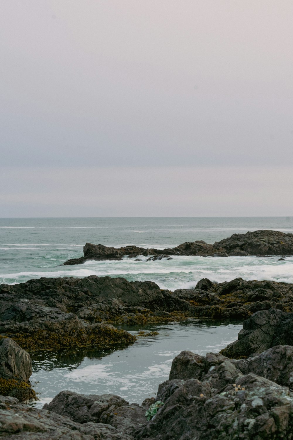 a person standing on a rocky beach with a surfboard