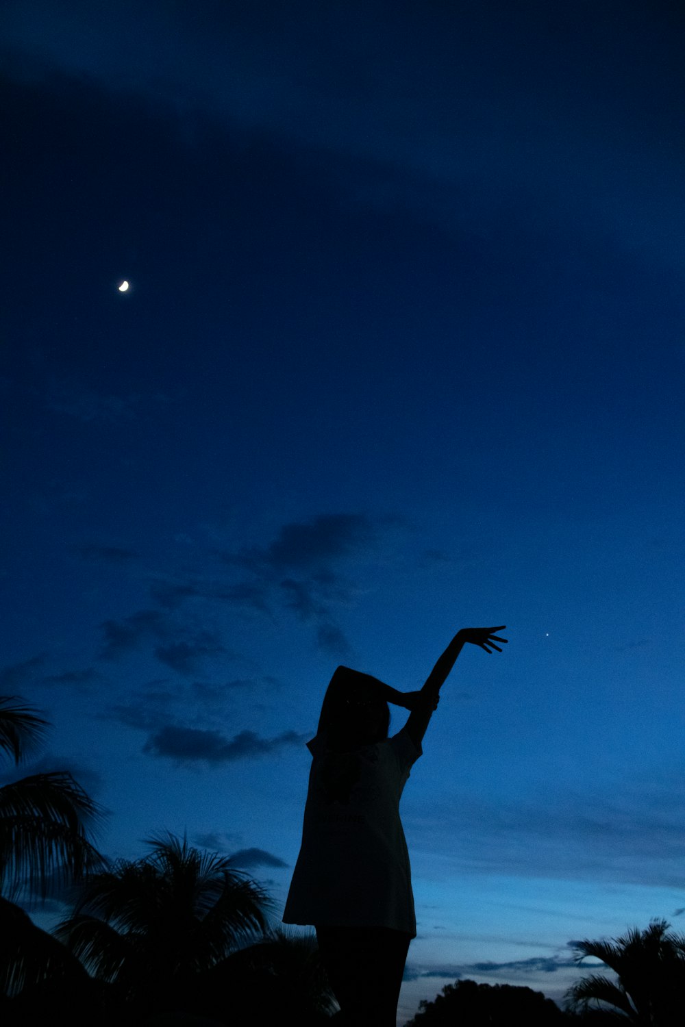 a woman reaching up into the sky at night