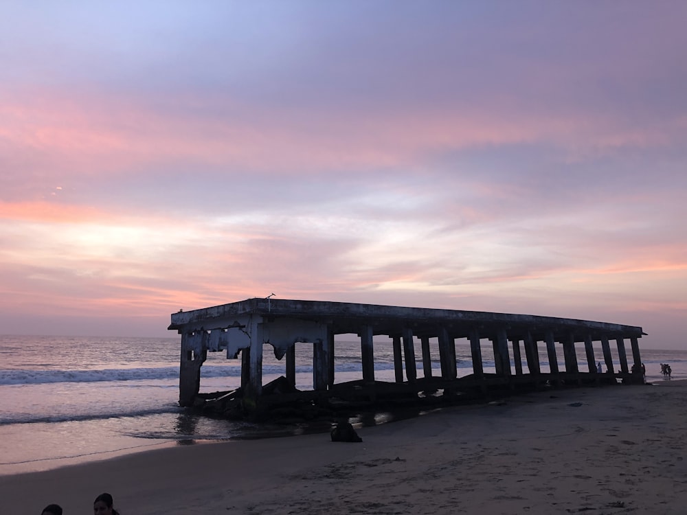 a pier sitting on top of a sandy beach next to the ocean