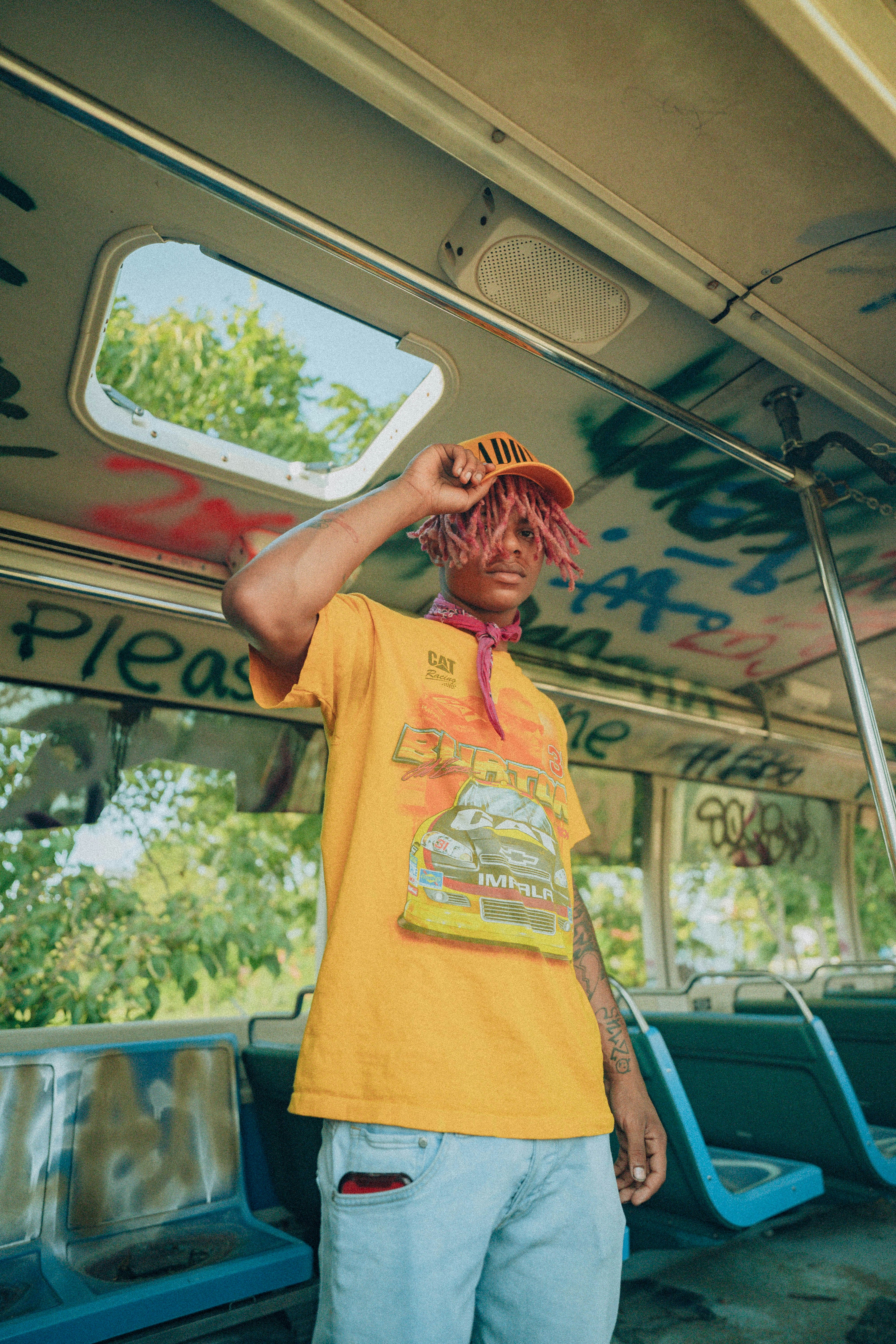 a man in a yellow shirt and hat standing on a bus