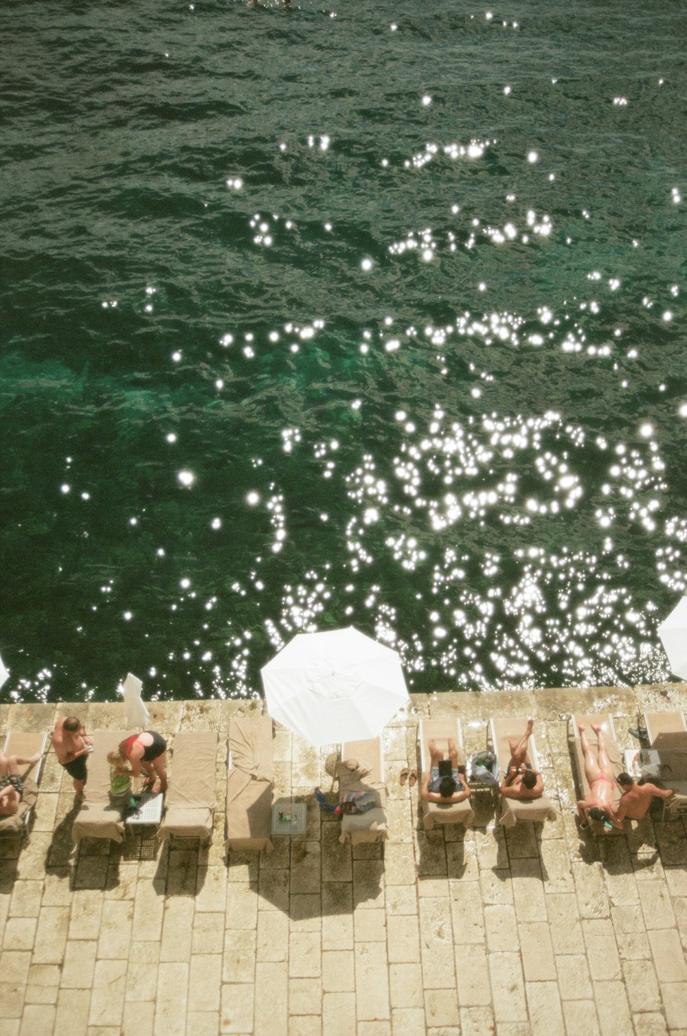 a group of people sitting on top of a pier next to the ocean