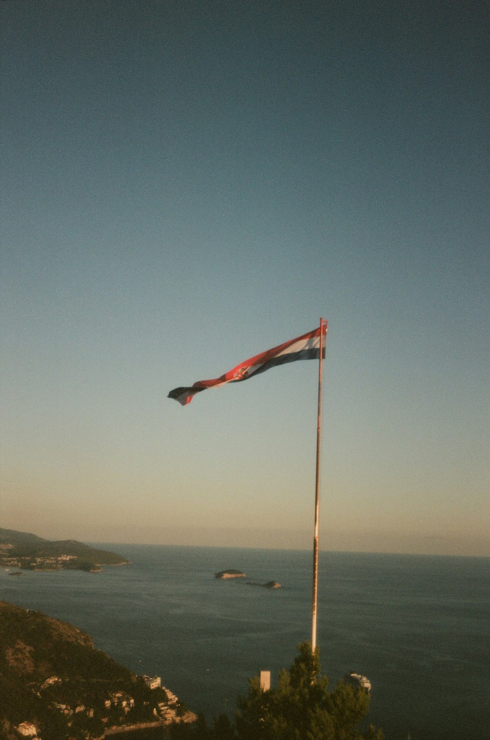 a flag on top of a hill overlooking a body of water