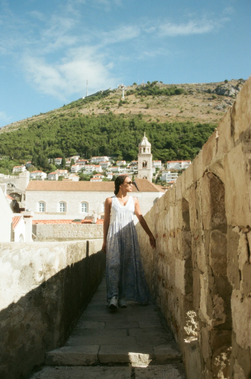 a woman is standing on a stone wall