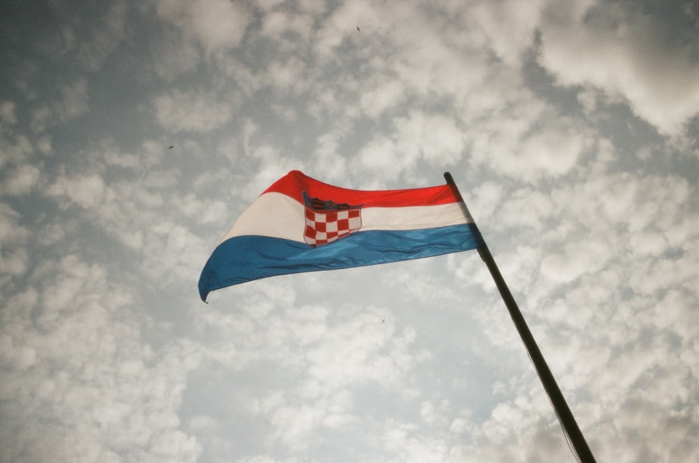 a flag flying high in the sky on a cloudy day