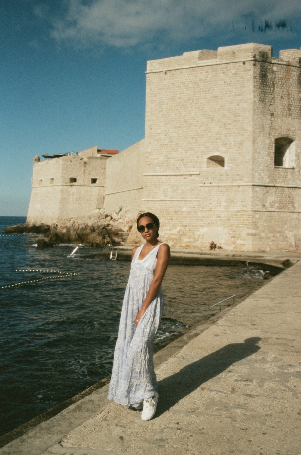 a woman in a white dress standing on a pier