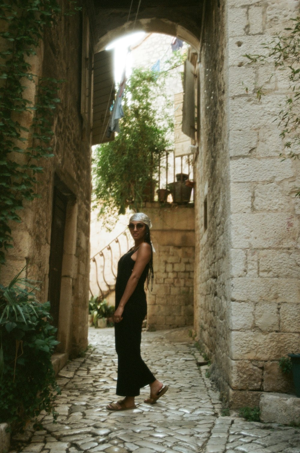 a woman is walking down a narrow alley way