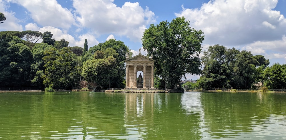 a lake with a gazebo surrounded by trees