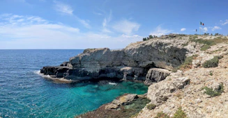 two people standing on the edge of a cliff overlooking the ocean
