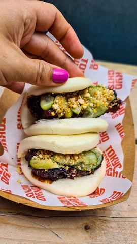 a person holding a plate of food on a table