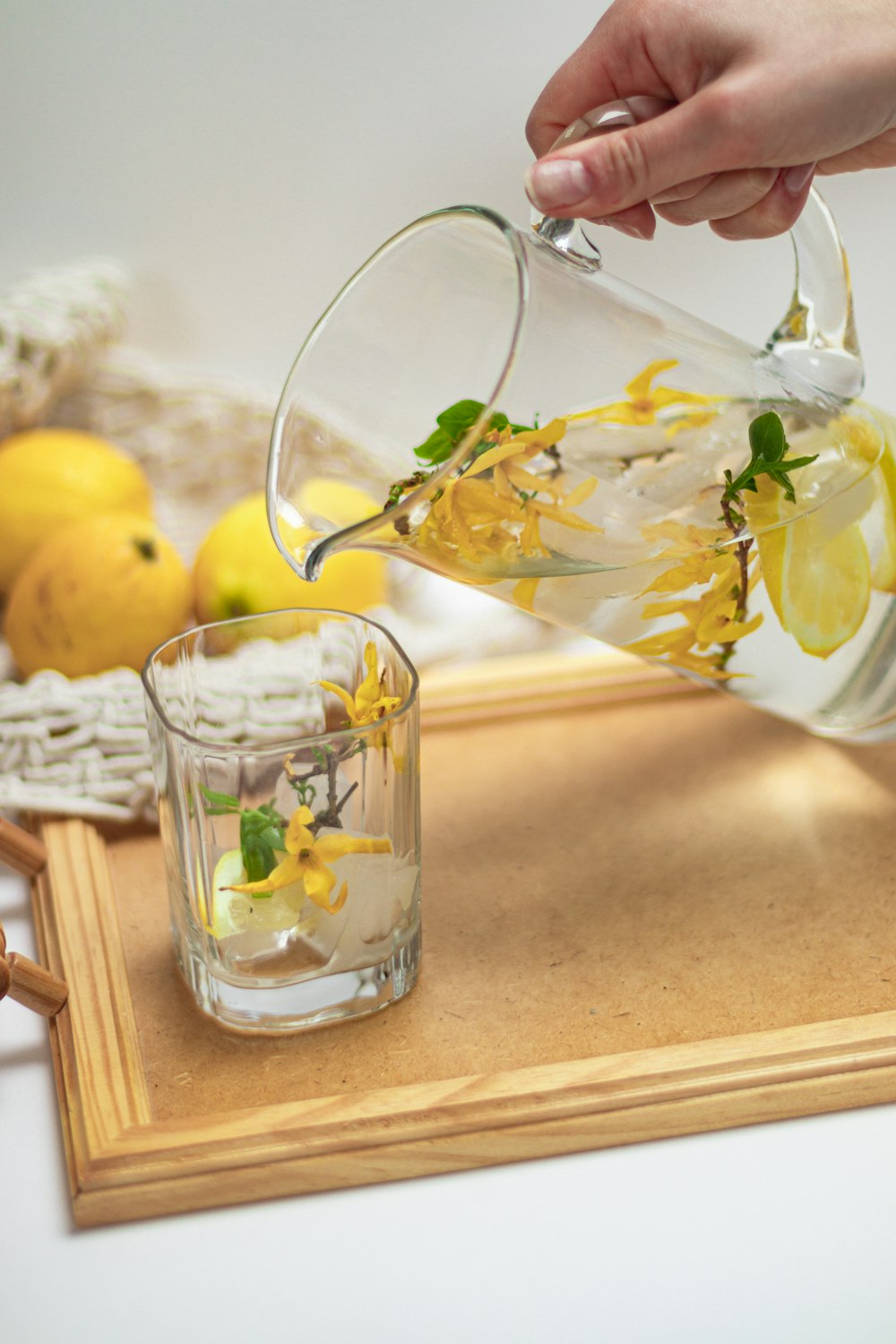 a person pouring water into a glass with lemons