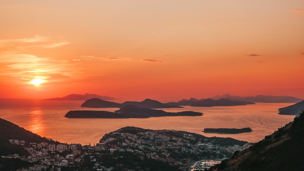 the sun is setting over a city and a body of water