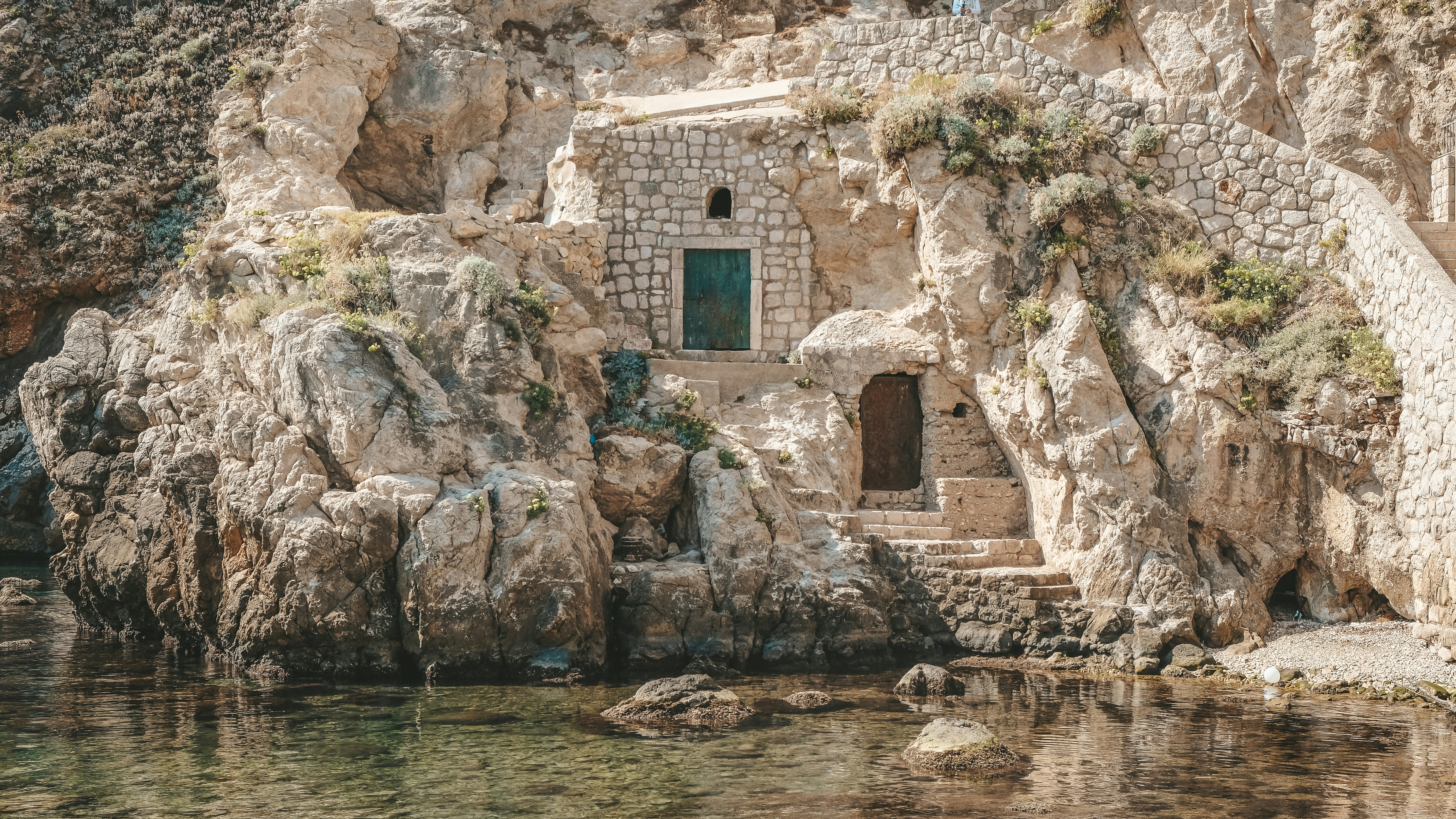 A building built into the side of a cliff next to a body of water