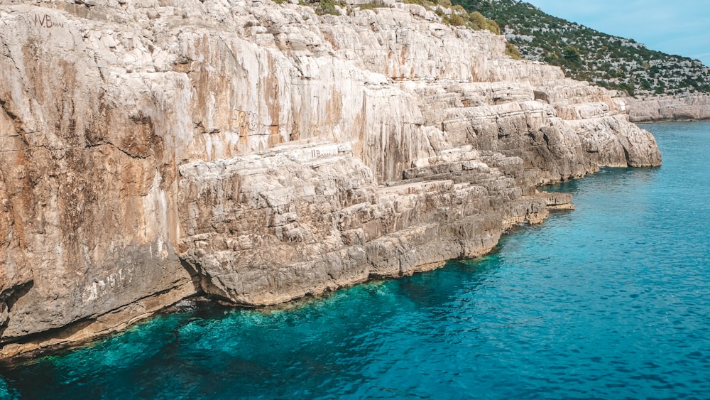 a rocky cliff next to a body of water