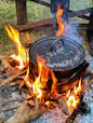 a pot on fire in a field next to a fence