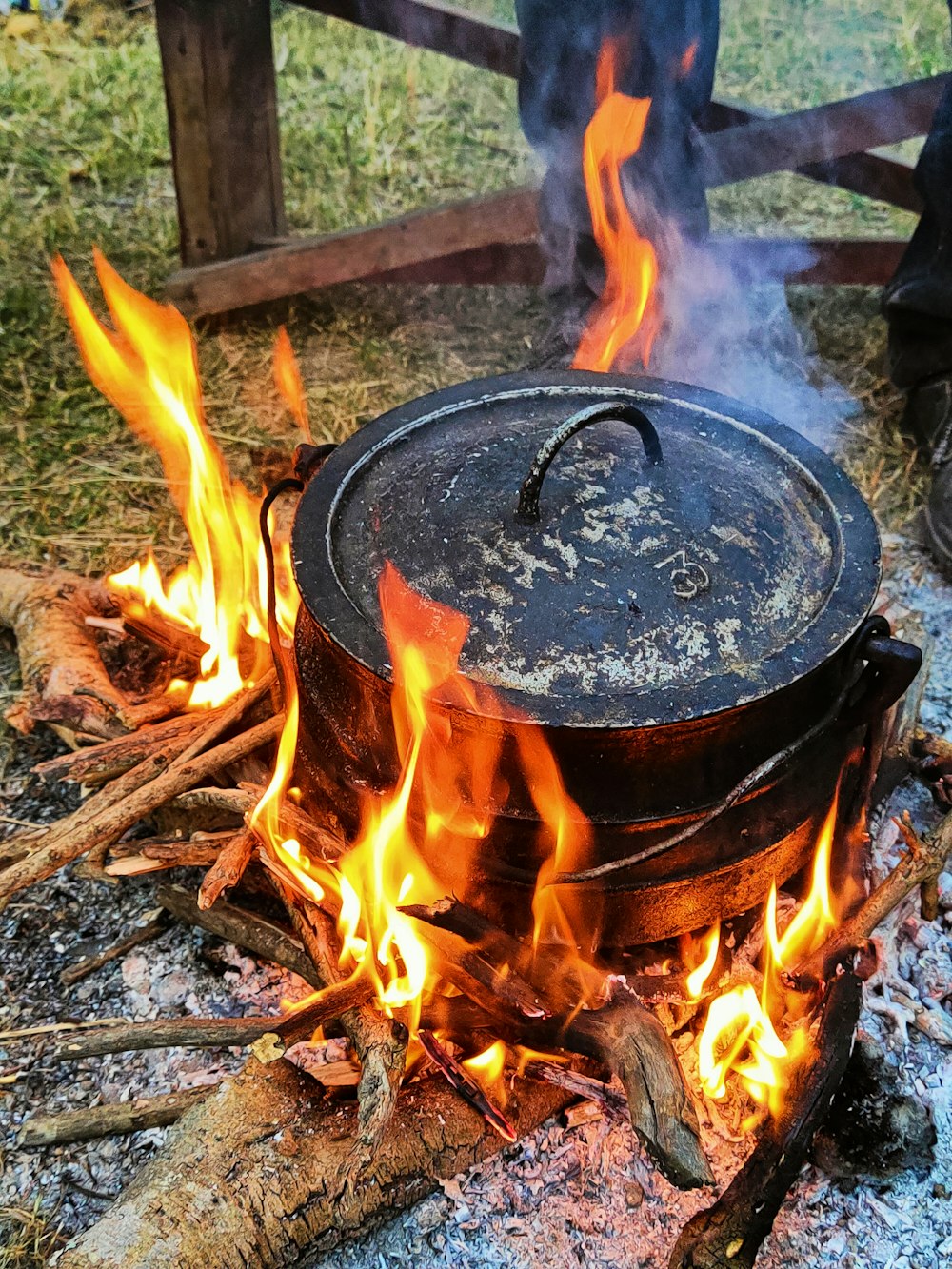 un pot en feu dans un champ à côté d’une clôture